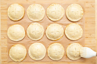 Brushing egg wash over the hand pies before baking