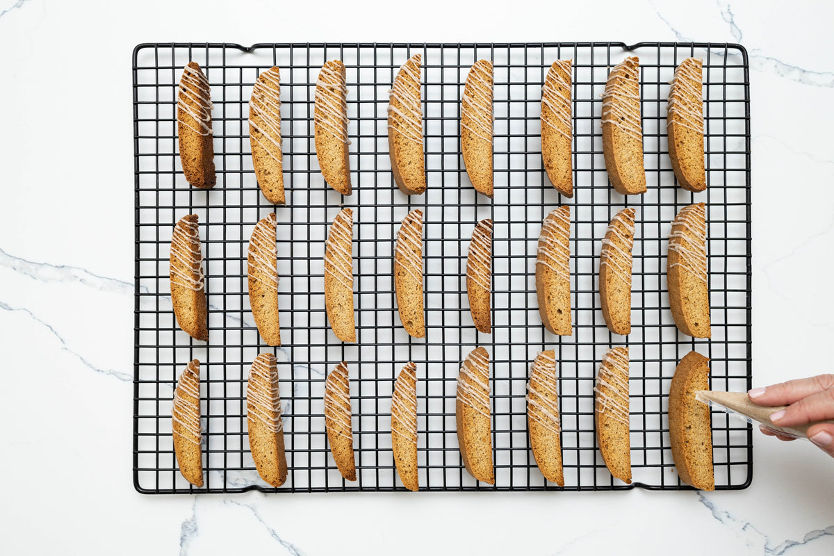 Drizzling icing over twice-baked biscotti on a cooling rack