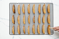Drizzling icing over twice-baked biscotti on a cooling rack