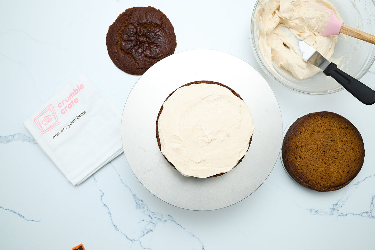 Spreading maple cinnamon frosting between the pumpkin cake layers