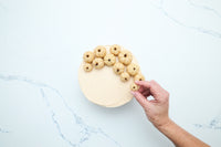 Placing marzipan pumpkins on top of the frosted cake