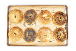 Assorted bagels on a baking tray with a white background