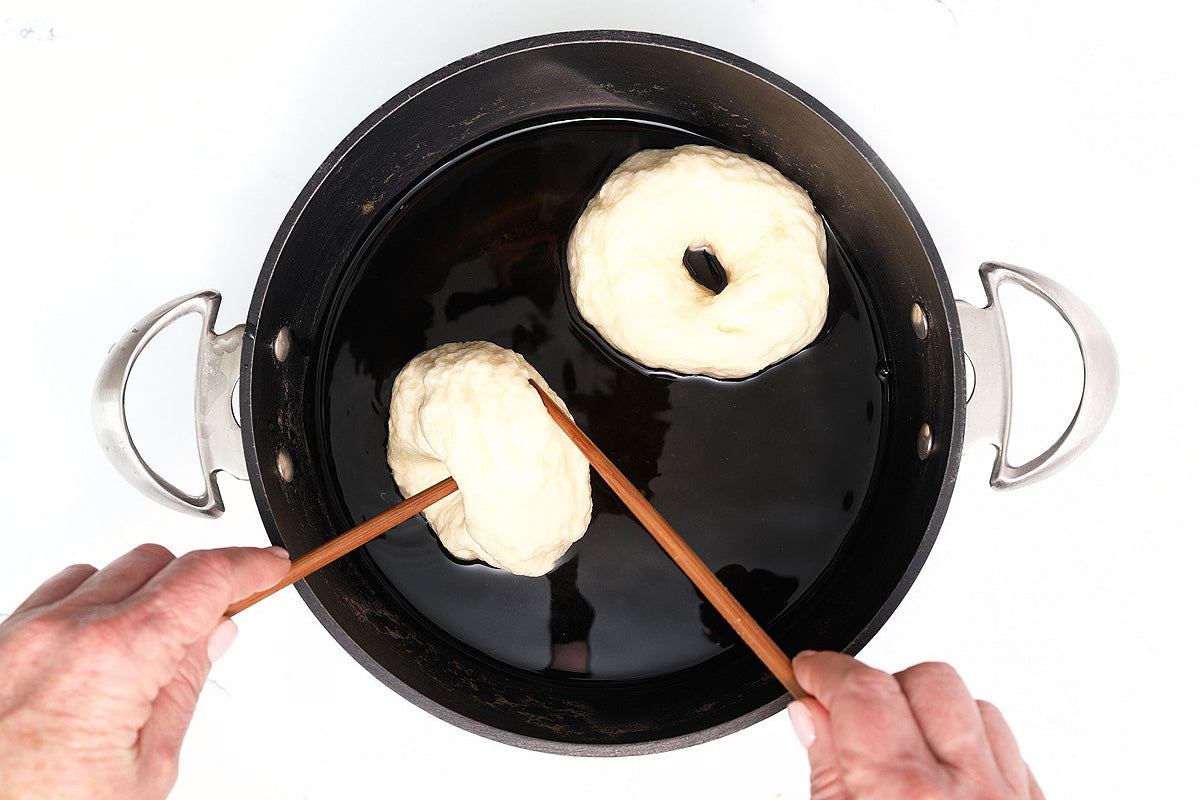 Boiling homemade bagels in water before baking as part of a New York style bagel baking kit
