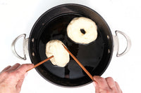 Boiling homemade bagels in water before baking as part of a New York style bagel baking kit