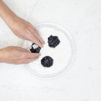 Rolling cookie dough balls in powdered sugar to create the crinkle finish