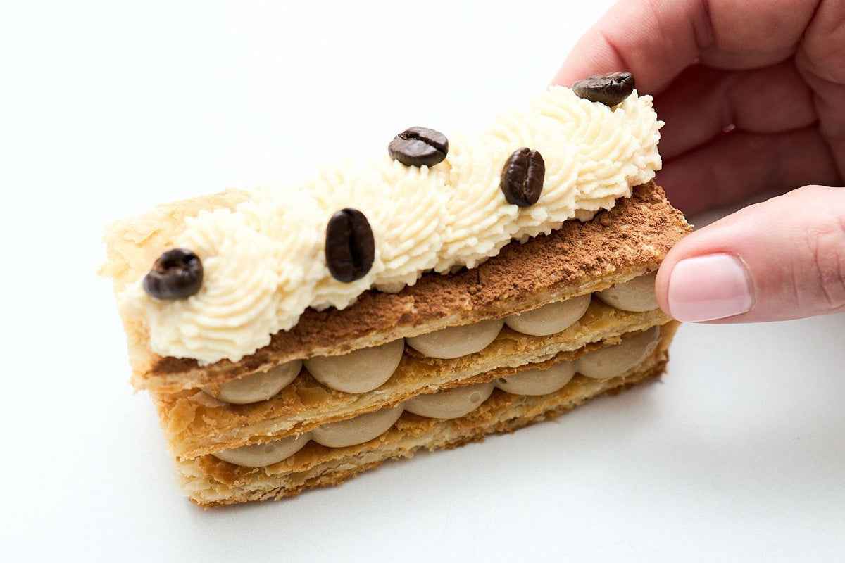 Tiramisu Napoleons: espresso pastry cream between puff pastry layers, topped with piped cream and coffee beans.